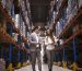 Business people walking through large distribution center and talking about increasing production and organization.
